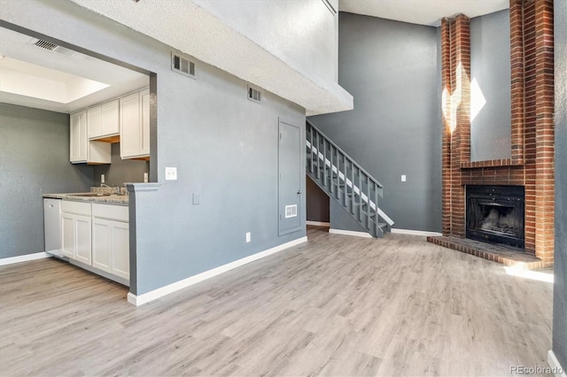 19192 E Wyoming Pl Unit 206, Aurora, CO 80017 - unfurnished living room with light wood-style flooring, stairs, baseboards, and a brick fireplace