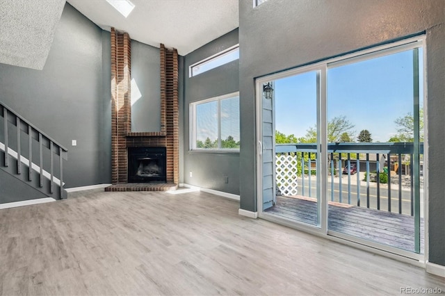 19192 E Wyoming Pl Unit 206, Aurora, CO 80017 - unfurnished living room with wood finished floors, baseboards, stairway, high vaulted ceiling, and a fireplace