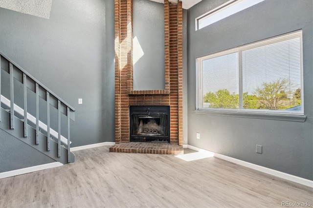 19192 E Wyoming Pl Unit 206, Aurora, CO 80017 - unfurnished living room featuring wood finished floors, healthy amount of natural light, a brick fireplace, and a towering ceiling