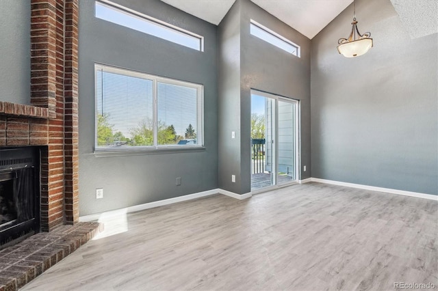 19192 E Wyoming Pl Unit 206, Aurora, CO 80017 - unfurnished living room with healthy amount of natural light, wood finished floors, a fireplace, baseboards, and high vaulted ceiling