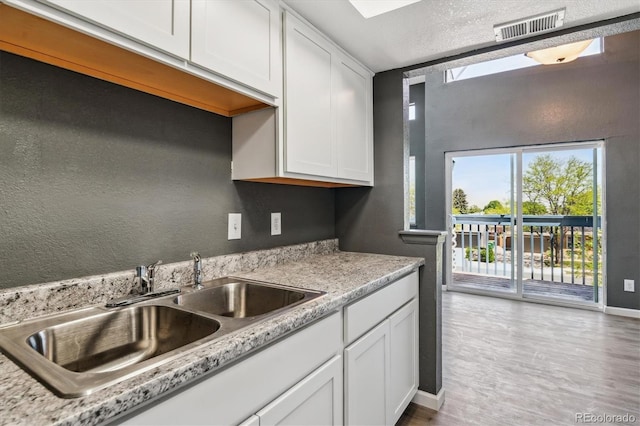 19192 E Wyoming Pl Unit 206, Aurora, CO 80017 - kitchen featuring a sink, white cabinetry, light countertops, and light wood-type flooring