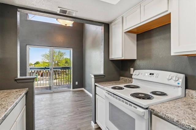 19192 E Wyoming Pl Unit 206, Aurora, CO 80017 - kitchen with electric range, healthy amount of natural light, white cabinetry, wood finished floors, and a textured wall