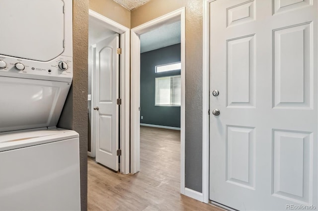 19192 E Wyoming Pl Unit 206, Aurora, CO 80017 - laundry room featuring stacked washer / drying machine, a textured wall, light wood-style flooring, and baseboards