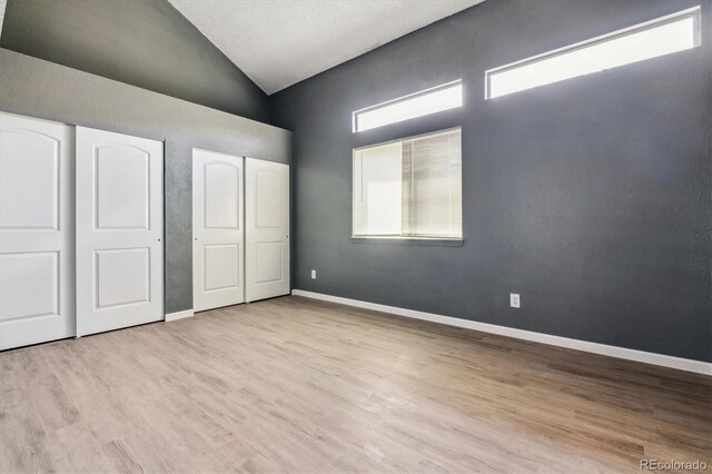 19192 E Wyoming Pl Unit 206, Aurora, CO 80017 - unfurnished bedroom with high vaulted ceiling, wood finished floors, baseboards, and two closets