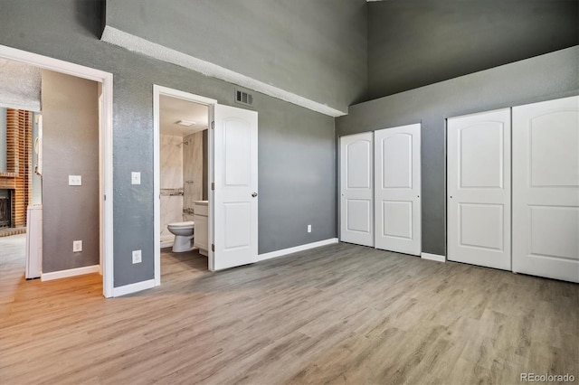 19192 E Wyoming Pl Unit 206, Aurora, CO 80017 - unfurnished bedroom with a high ceiling, baseboards, light wood finished floors, multiple closets, and connected bathroom