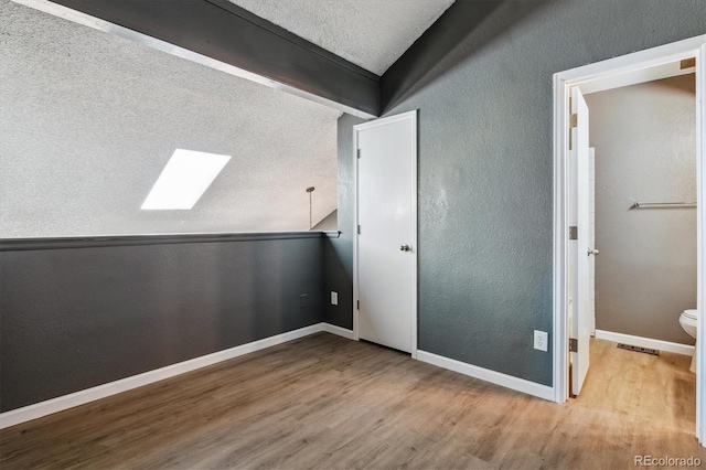 19192 E Wyoming Pl Unit 206, Aurora, CO 80017 - unfurnished bedroom with a skylight, wood finished floors, vaulted ceiling, baseboards, and a textured ceiling