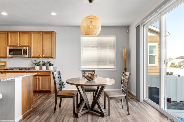 kitchen featuring stainless steel appliances, light stone countertops, decorative light fixtures, and wood-type flooring