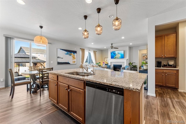 kitchen featuring pendant lighting, an island with sink, stainless steel dishwasher, and a healthy amount of sunlight