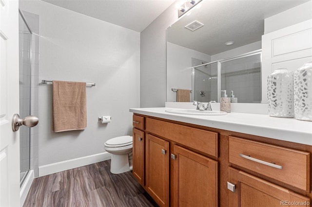 bathroom featuring vanity, a textured ceiling, hardwood / wood-style flooring, walk in shower, and toilet