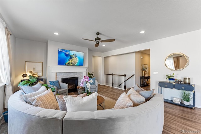 living room featuring a fireplace, ceiling fan, and wood-type flooring