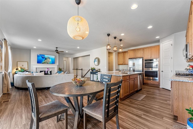 dining space featuring wood-type flooring, sink, and ceiling fan