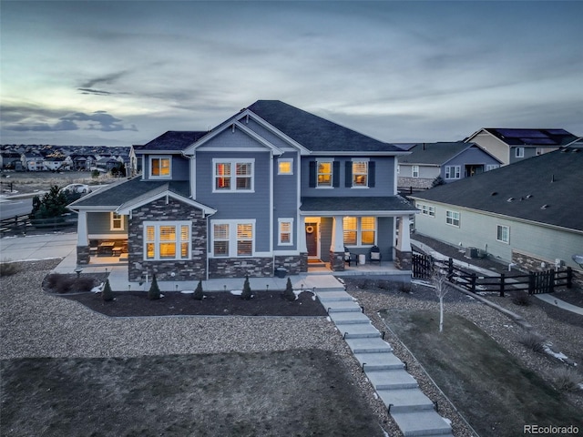 rear view of property featuring a patio area, fence, and stone siding