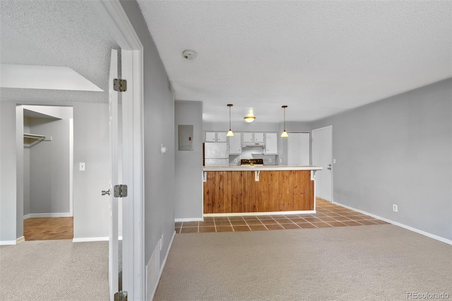 kitchen with white refrigerator, kitchen peninsula, light colored carpet, a textured ceiling, and white cabinets