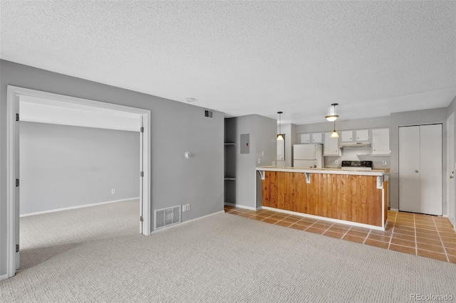 kitchen with black stove, a kitchen island, white fridge, decorative light fixtures, and white cabinets