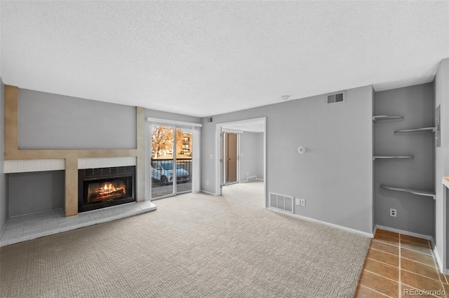 unfurnished living room with a textured ceiling and a tiled fireplace