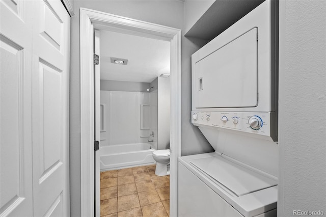 washroom with stacked washer / drying machine and light tile patterned flooring