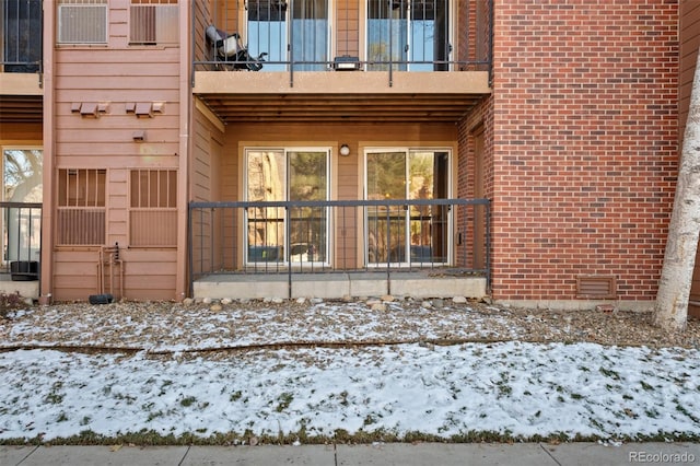 snow covered property entrance with a balcony