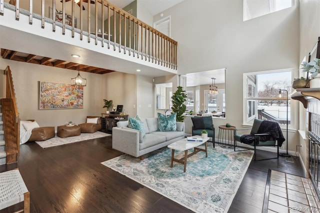 living room featuring dark hardwood / wood-style flooring, a fireplace, a high ceiling, and a chandelier