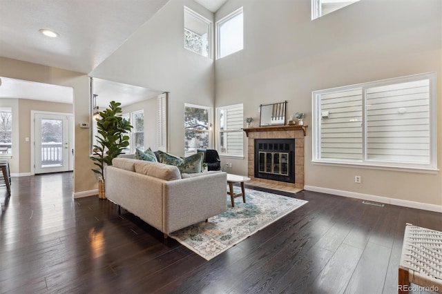 living room featuring dark hardwood / wood-style flooring, a fireplace, and a towering ceiling