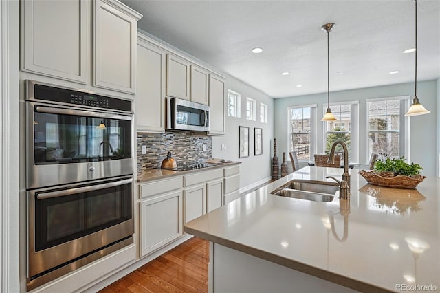 6013 Eldora St, Golden, CO 80403 - kitchen with stainless steel appliances, backsplash, light wood-style floors, light countertops, and recessed lighting