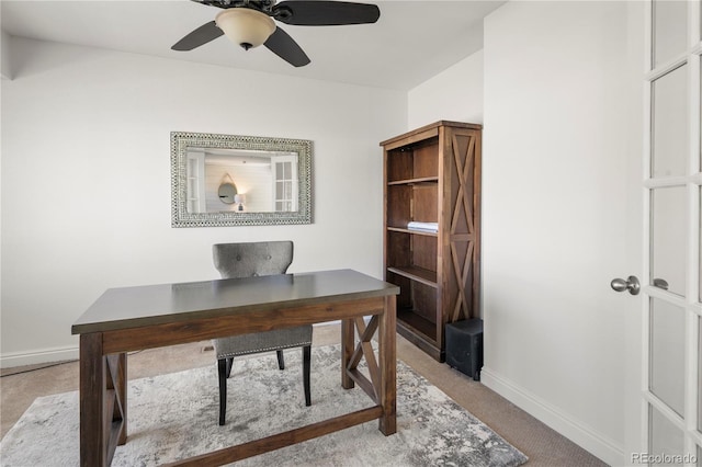 office area with a ceiling fan, light colored carpet, and baseboards