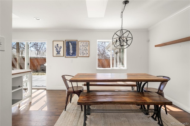 dining room with a notable chandelier, ornamental molding, wood finished floors, and baseboards