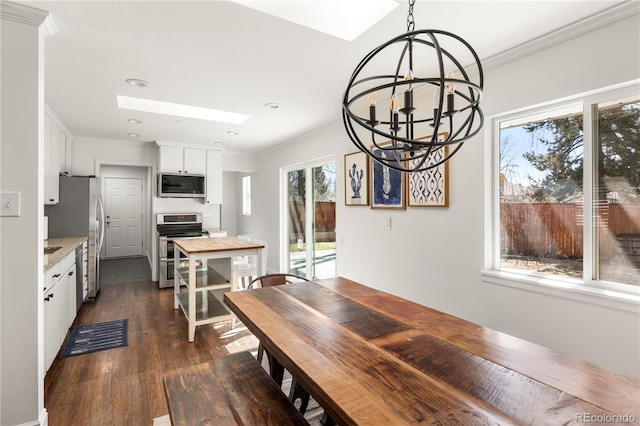 dining space featuring a skylight, crown molding, dark wood-style flooring, and a notable chandelier