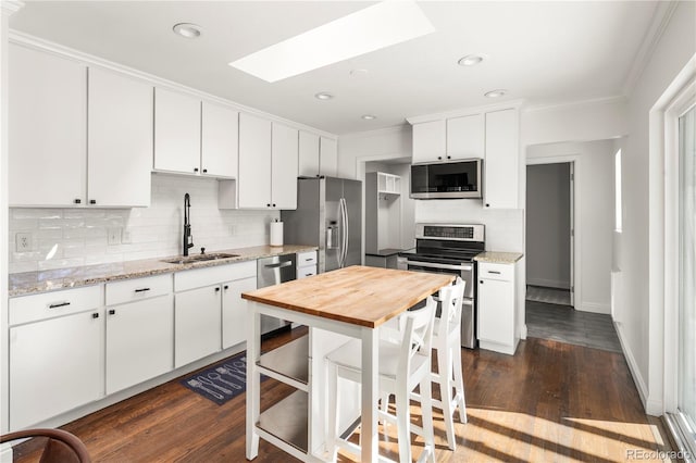 kitchen featuring a skylight, ornamental molding, stainless steel appliances, and a sink