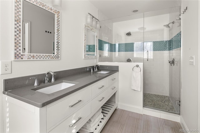 bathroom with double vanity, a stall shower, and a sink