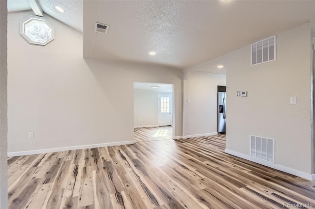 empty room featuring a textured ceiling and light hardwood / wood-style flooring