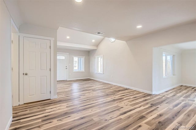 empty room with lofted ceiling and light hardwood / wood-style floors