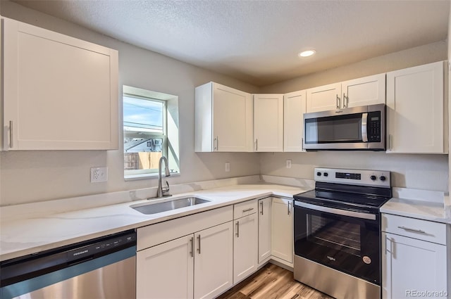 kitchen featuring white cabinetry, appliances with stainless steel finishes, sink, and light stone counters