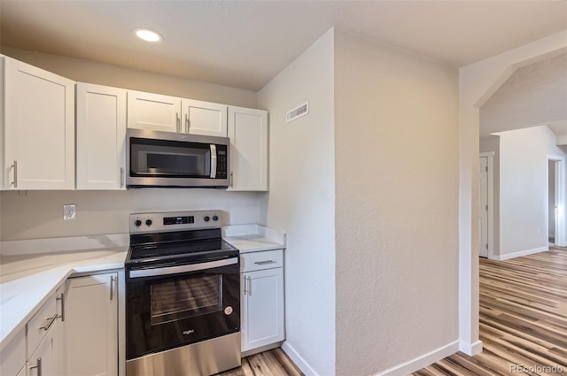 kitchen with white cabinetry, light stone countertops, light hardwood / wood-style flooring, and stainless steel appliances