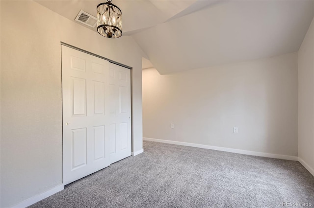 unfurnished bedroom featuring vaulted ceiling, carpet, a chandelier, and a closet