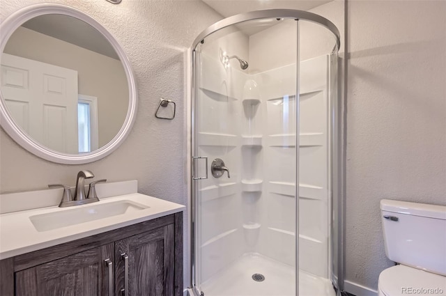 bathroom with vanity, a shower with door, and toilet