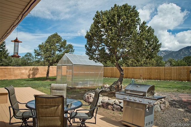 1564 Wagon Wheel Rd, Crestone, CO 81131 - fenced backyard with a greenhouse, grilling area, a deck with mountain view, an outbuilding, and outdoor dining space