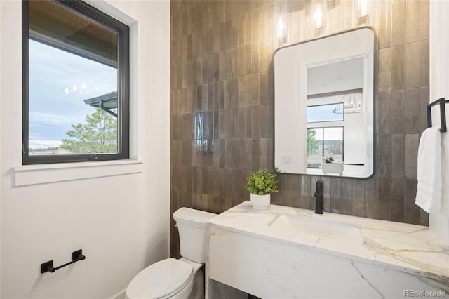 bathroom with vanity, tile walls, and toilet