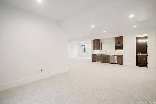 unfurnished living room with sink, light carpet, and wine cooler