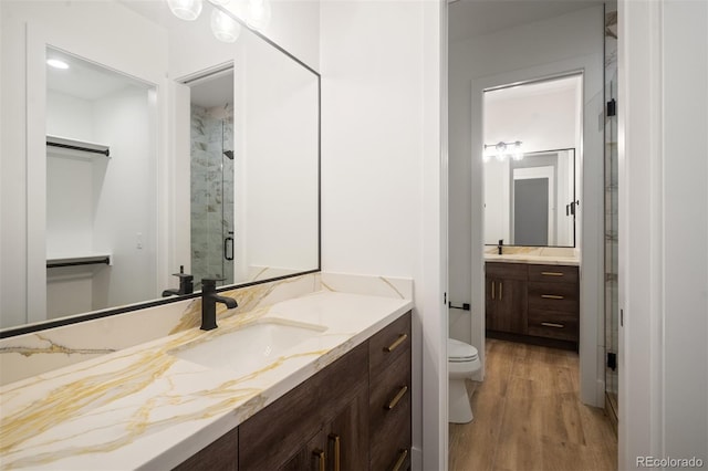 bathroom featuring vanity, a shower with shower door, hardwood / wood-style floors, and toilet