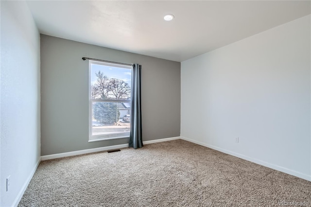 carpeted empty room featuring visible vents and baseboards