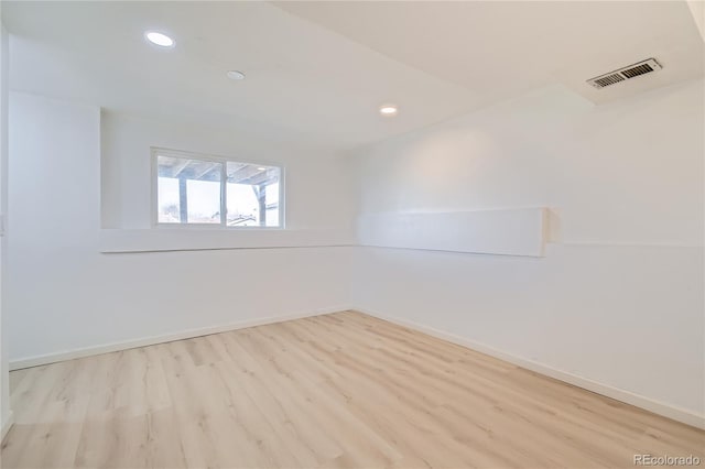 empty room featuring light wood-style flooring, visible vents, baseboards, and recessed lighting