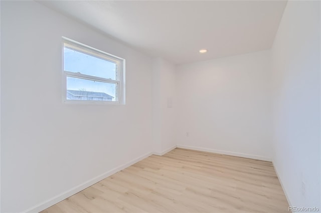 empty room featuring light wood finished floors, baseboards, and recessed lighting