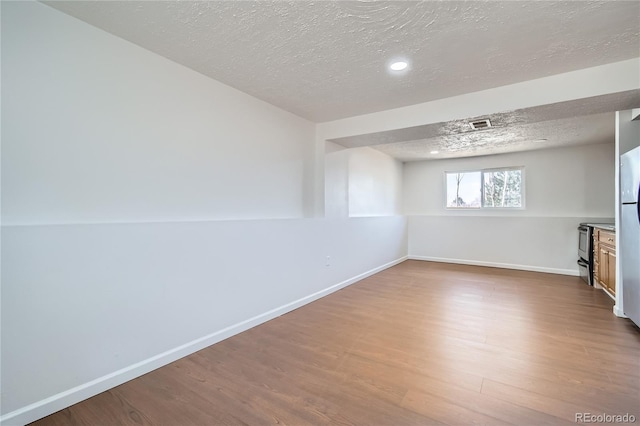 interior space with visible vents, a textured ceiling, baseboards, and wood finished floors