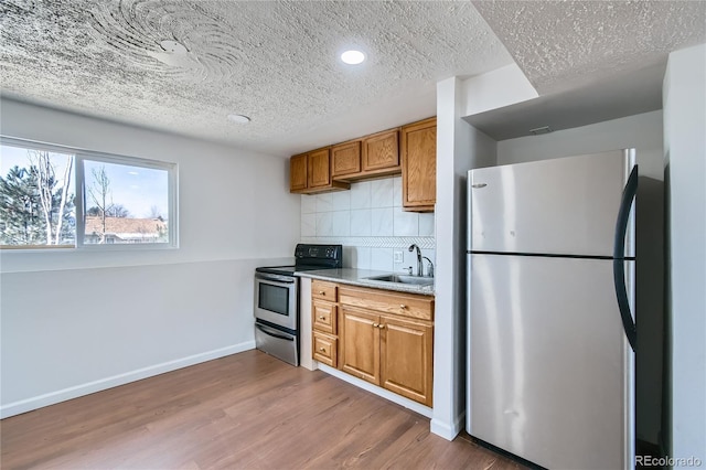 kitchen featuring stainless steel appliances, a sink, light countertops, brown cabinets, and dark wood-style floors