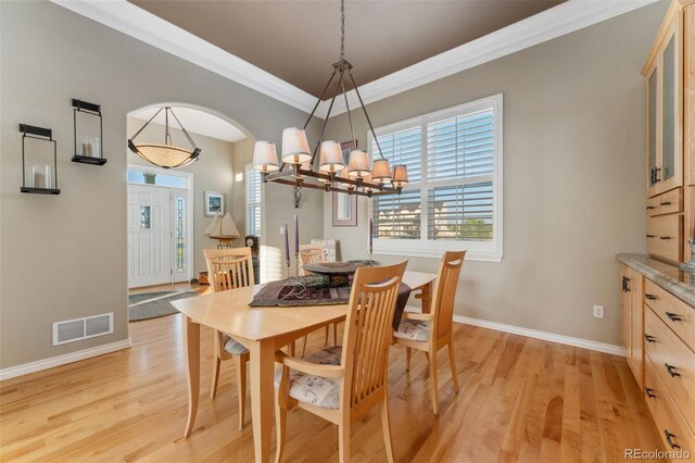 881 Kirby Ct, Watkins, CO 80137 - dining area with light wood-type flooring, crown molding, a chandelier, and arched walkways