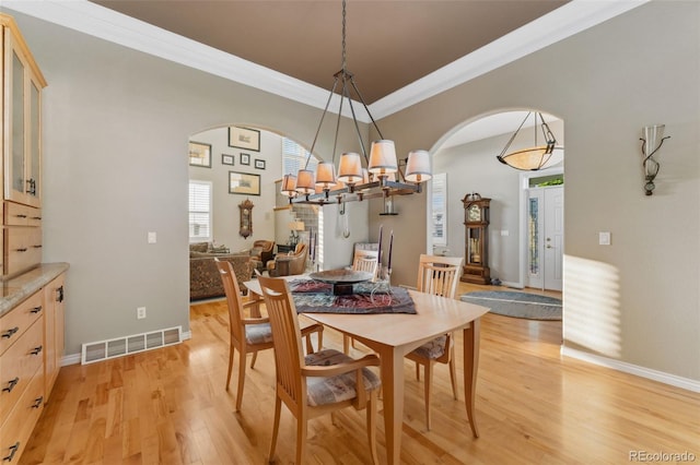 881 Kirby Ct, Watkins, CO 80137 - dining room featuring arched walkways, light wood-style floors, ornamental molding, and a chandelier