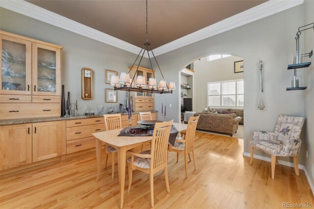 881 Kirby Ct, Watkins, CO 80137 - dining room featuring arched walkways, ornamental molding, light wood-type flooring, and a chandelier