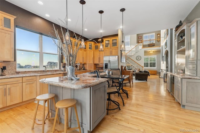 881 Kirby Ct, Watkins, CO 80137 - kitchen featuring a kitchen bar, stainless steel refrigerator with ice dispenser, light wood-style flooring, light brown cabinets, and recessed lighting
