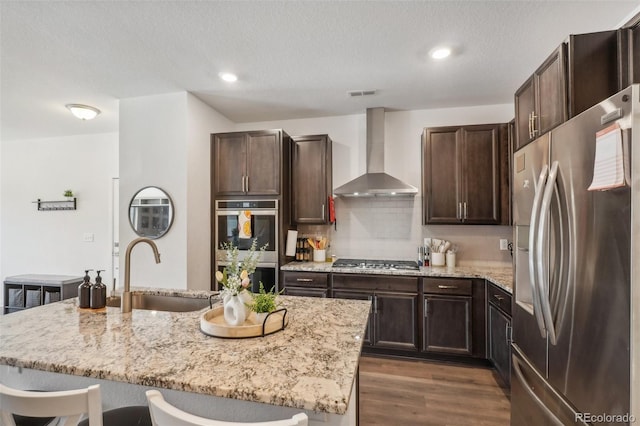 27593 E 1st Pl, Aurora, CO 80018 - kitchen featuring stainless steel appliances, wall chimney exhaust hood, a sink, light stone counters, and recessed lighting