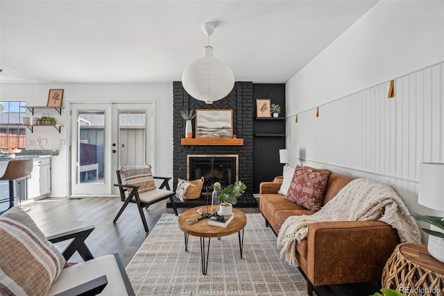 living room featuring a brick fireplace, light wood-type flooring, and french doors